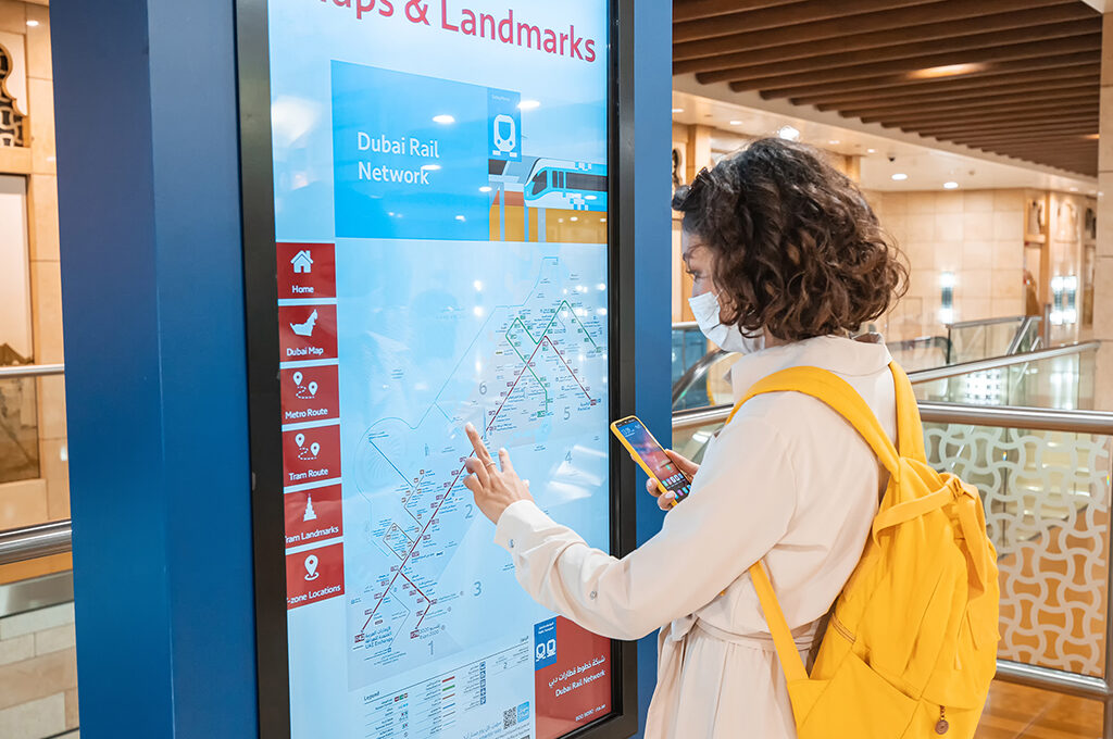 A solo female traveller checking the Dubai Rail Network map on an interactive display; is Dubai safe for solo female travellers is a common question, and the city's accessible public transport highlights why it is.