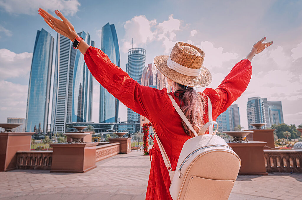 A solo female traveller in a red dress posing against the modern Dubai skyline, illustrating that is Dubai safe for solo female travellers is often answered by the city's welcoming and vibrant tourist atmosphere.