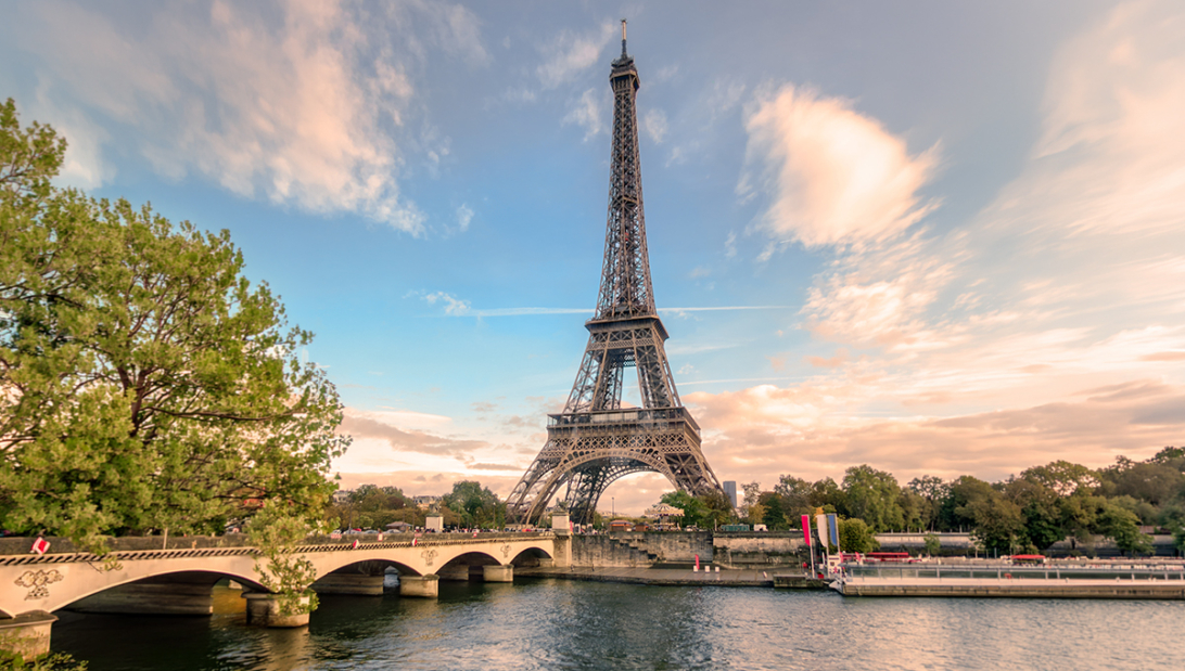 A scenic view of the Eiffel Tower rising above a bridge over the Seine River in Paris, which is a popular area to consider when deciding where to stay in Paris.