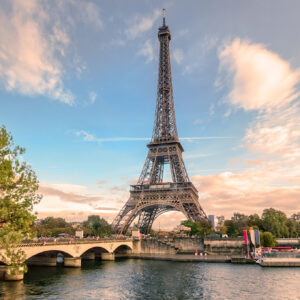 A scenic view of the Eiffel Tower rising above a bridge over the Seine River in Paris, which is a popular area to consider when deciding where to stay in Paris.