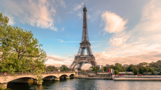 A scenic view of the Eiffel Tower rising above a bridge over the Seine River in Paris, which is a popular area to consider when deciding where to stay in Paris.