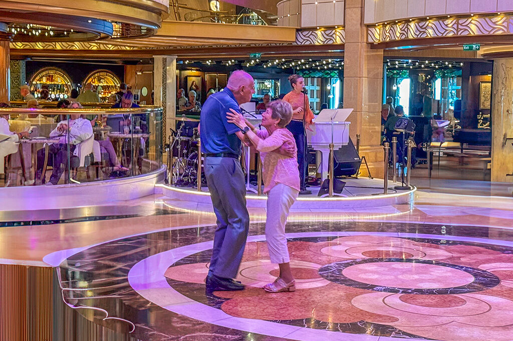 An elderly couple dancing together in a lavish lounge, showcasing the onboard entertainment found on the best luxury cruise lines for couples.