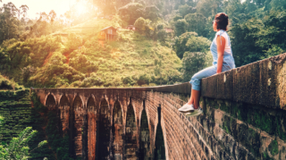 A solo female traveller enjoying a view from the iconic Nine Arch Bridge, showcasing the scenic and rewarding experiences that lead many to ask is sri lanka safe for solo female travellers.