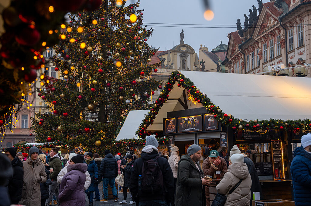 People gathering around festively decorated food and drink stalls with a giant decorated Christmas tree at one of the best European Christmas markets.