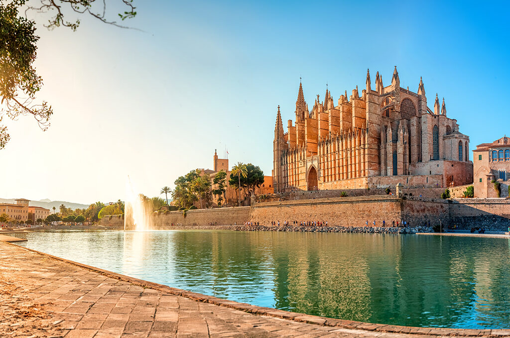 Historic cathedral reflecting in a waterfront pool with a fountain during golden hour in Spain is one of the most popular holiday destinations.