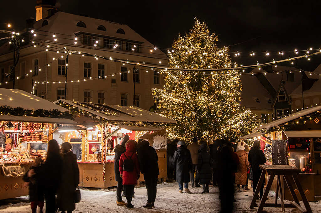 A snowy town square filled with festive wooden stalls and a towering glowing Christmas tree, capturing the magic of the best European Christmas markets.