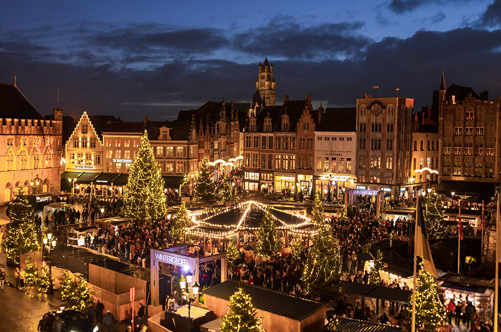 An aerial evening view of a European city square packed with glowing holiday stalls, representing one of the best European Christmas markets.