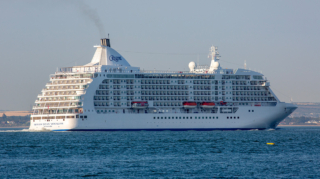A luxury Regent Seven Seas Voyager cruise ship sailing on blue ocean waters, representing options available when booking the best cruise lines from Southampton.