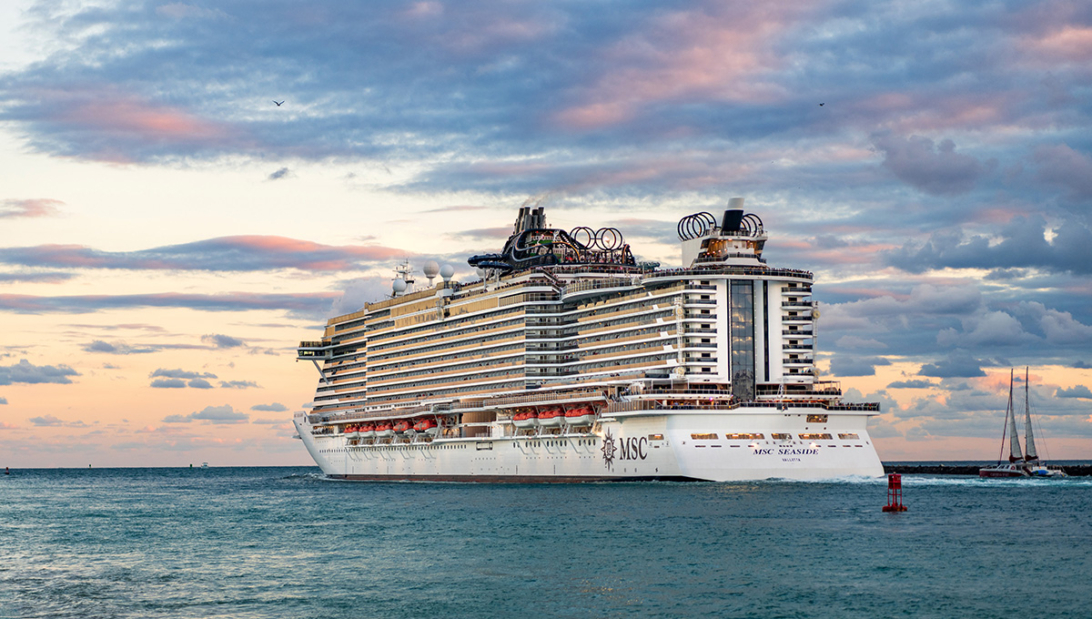 A large cruise ship sailing on the ocean during a colorful sunset, illustrating the best time to book a cruise for scenic ocean voyages.