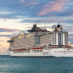 A large cruise ship sailing on the ocean during a colorful sunset, illustrating the best time to book a cruise for scenic ocean voyages.