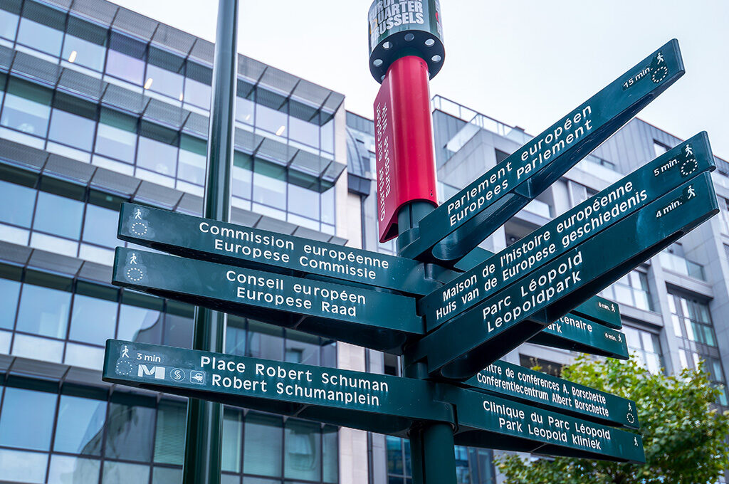 Street direction signs pointing toward major European Union institutions in the modern district, relevant for professionals evaluating where to stay in Brussels.