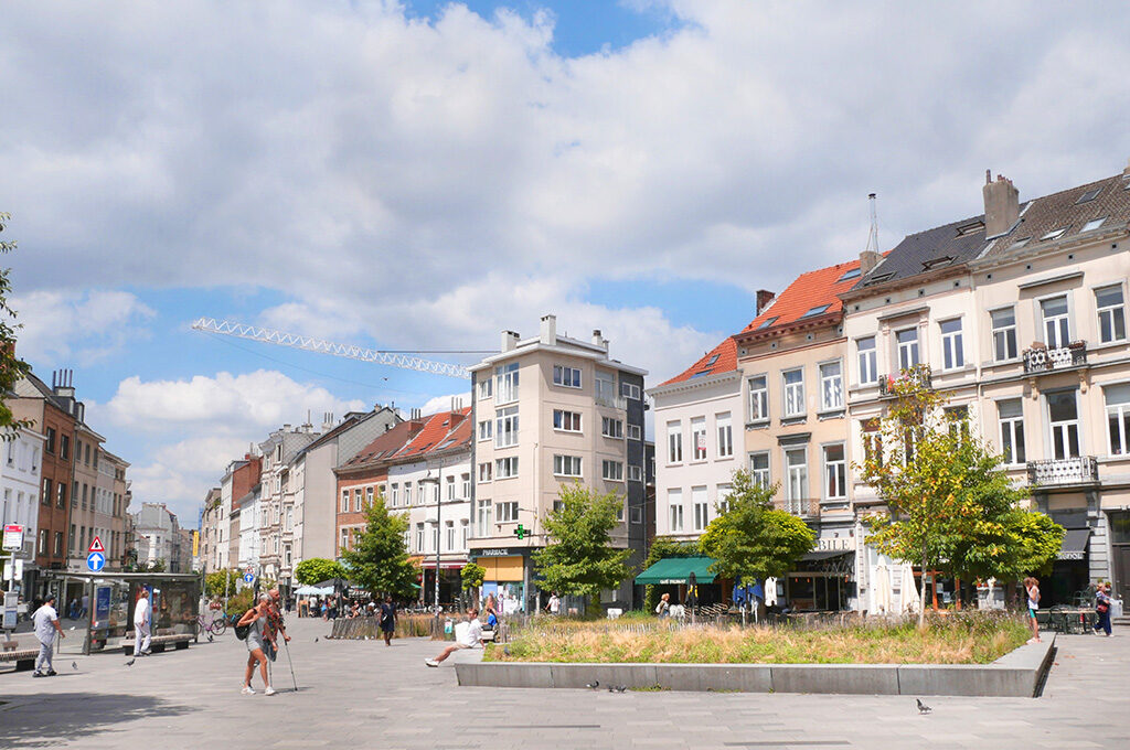 A lively public square in Ixelles featuring outdoor cafe seating and classic architecture, ideal for tourists exploring where to stay in Brussels.