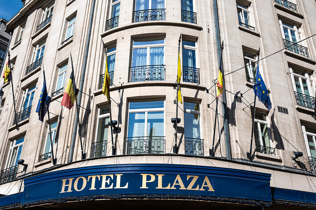 The grand historical facade and entrance of a classic European hotel on Avenue Adolphe Max, showcasing accommodation options for where to stay in Brussels.
