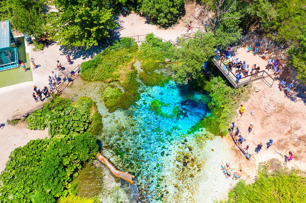 Vibrant, deep blue water bubbling up from the karst spring of the Blue Eye natural monument, a popular scenic attraction near the best places to stay in Albania.