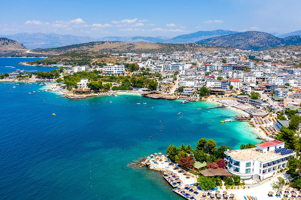 Crystal-clear turquoise waters and white sandy shores of Bora Bora Beach in Ksamil, showcasing a top coastal destination among the best places to stay in Albania.