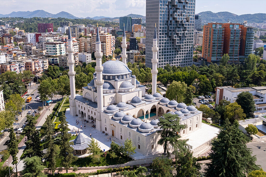 High-angle drone shot over Tirana's skyline, featuring Skanderbeg Square and modern architecture, highlighting a central hub among the best places to stay in Albania.