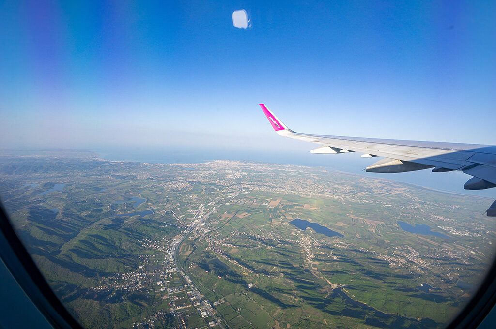 Aerial perspective from an airplane window looking down at clouds above Tirana, Albania, as passengers arrive to explore the best places to stay in Albania.
