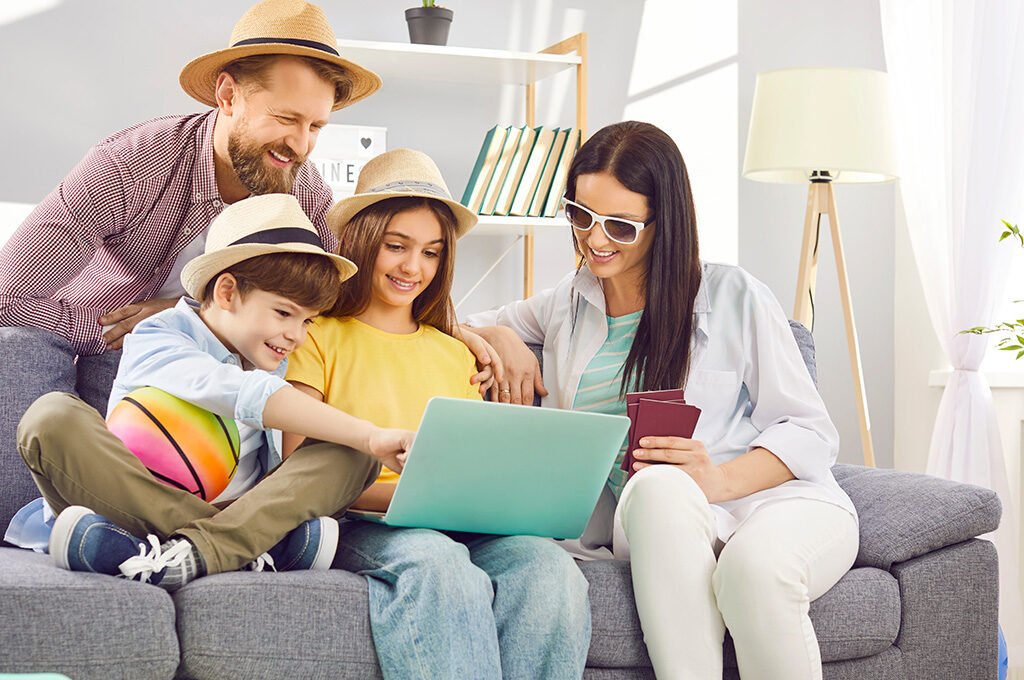 A family sitting together on a couch looking at a laptop to plan a vacation, demonstrating people searching online for when is the best time to book a cruise.