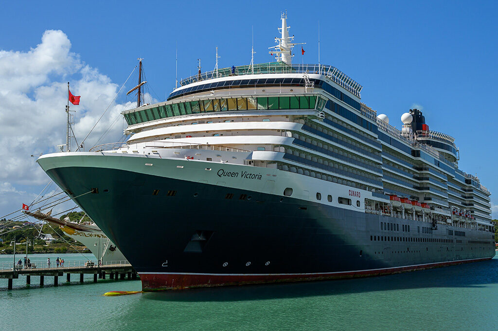 The Cunard Queen Victoria cruise ship docked by a pier on calm water, highlighting a classic choice for the best cruise lines from Southampton.