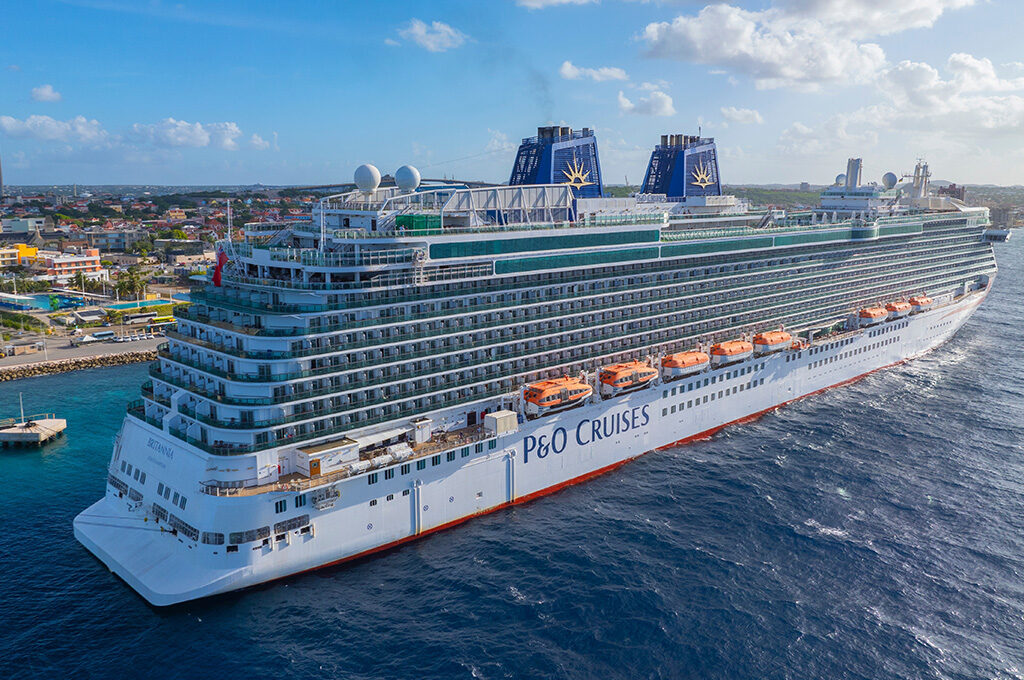 A P&O Cruises ship sailing near a coastal city and harbor, exemplifying top options among the best cruise lines from Southampton.