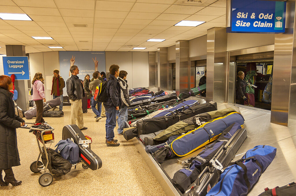 Skis and golf bag being checked in at airport baggage counter,British Airways Baggage Policy - VGUK Blog