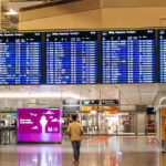 Digital flight departure boards displaying Lufthansa flight schedules at Munich Airport Terminal 2, a major aviation hub among the busiest airports in Europe.