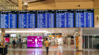 Digital flight departure boards displaying Lufthansa flight schedules at Munich Airport Terminal 2, a major aviation hub among the busiest airports in Europe.