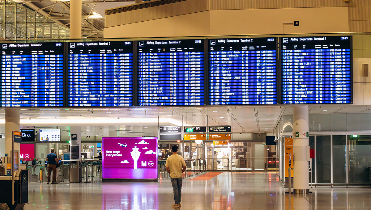 Digital flight departure boards displaying Lufthansa flight schedules at Munich Airport Terminal 2, a major aviation hub among the busiest airports in Europe.