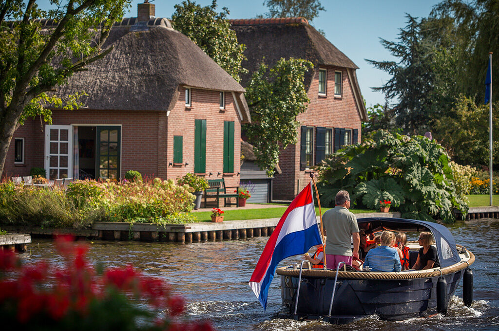 Traditional red brick Dutch house on canal in Giethoorn village - charming places to visit in Netherlands with family featuring the “Venice of the North” with whisper boats.