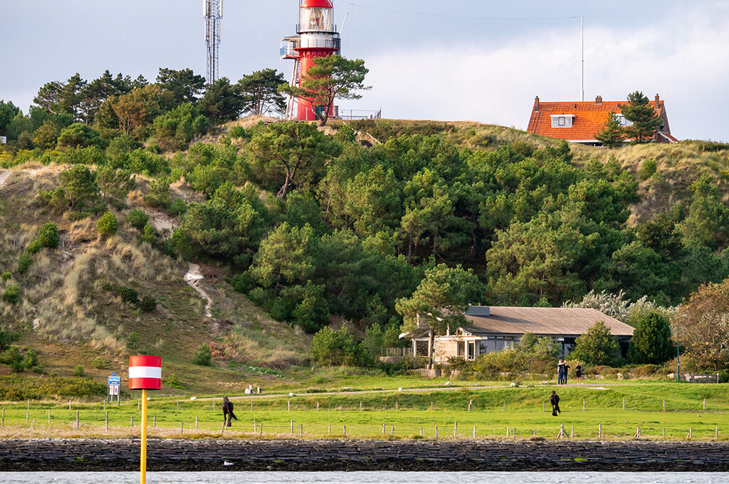 Coastal lighthouse on sand dune at Vlieland island - quiet places to visit in Netherlands with family reachable by ferry, car-free and family-friendly.
