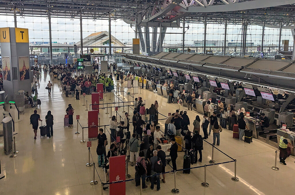 Passengers queuing with luggage at check-in counters in a crowded terminal hall, representing international travel at the busiest airports in Europe and major global transport hubs.