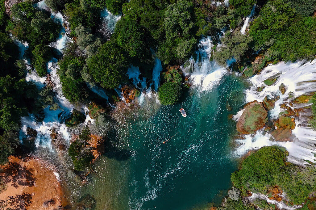 Top-down aerial view of Kravica Waterfall and turquoise pool, a natural gem near the best Eastern European cities to visit.