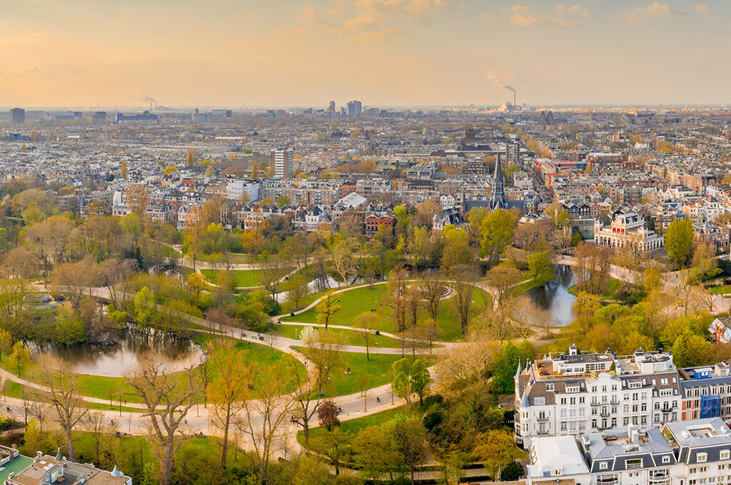 Amsterdam Panoramic View Historic City Center Stock Photo 2507490843 | Shutterstock 
If you're weighing up places to visit in Netherlands with family this year, you're looking at one of the easiest short-haul trips going, flat, bike-friendly, English is spoken everywhere, and you're never more than an hour from somewhere genuinely brilliant for kids. A Netherlands family holiday doesn't need a hire car or a complicated itinerary; it works just as well as a city break with day trips bolted on, and the country rewards families who build in a bit of slack rather than racing between attractions.
Is Netherlands Worth Visiting with Family?
Mother Her Child Walks Between Purple Stock Photo 105311111 | Shutterstock 
Short answer: yes, and more than people expect going in. Every family we've spoken to who's tried it says the same thing,it over-delivers against expectations. The terrain is flat enough that even a reluctant eight-year-old can manage a bike ride without complaint, flight time from the UK sits under two hours from most regional airports, and the attractions here are genuinely built with kids in mind rather than just tolerating them. This guide covers the specific places that make that true.
Top Places to Visit in the Netherlands with Family
Madurodam: Holland in Miniature
Netherlands Den Haag Miniature Park Madurodamjuly Stock Photo 1326512273 | Shutterstock 
Madurodam is the one families don't expect to love as much as they do. It's a miniature park just outside The Hague where entire Dutch cities, Schiphol Airport and a working network of canals are rebuilt at 1:25 scale, with real water running through tiny locks and boats drifting past buildings you can nearly see into. It's less about thrill and more about the kind of close-up wonder that keeps younger kids occupied for hours without a single queue. Visit in summer and the flowerbeds between the model buildings are in full bloom, which makes the whole park look better in photos than it has any right to.
Amsterdam's Family Attractions
Amsterdam's family attractions are concentrated enough that a loose day plan beats a rigid itinerary.
Vondelpark
Aerial View Vondelpark Amsterdam Stock Photo 1378371368 | Shutterstock 
The city's biggest green space is built for exactly this kind of day: wide paths for bikes and scooters, open grass for a picnic, a proper playground, and enough room that nobody's tripping over anyone else, though it is the park every local uses too, so finding a quieter corner near the lake is worth the five-minute walk.
NEMO Science Museum
Amsterdam Netherlands June 2 2023 External Stock Photo 2356447331 | Shutterstock 
This is the one every reviewer agrees on, and for good reason: the exhibits are hands-on rather than look-but-don't-touch, spread across several floors with a different theme each level. It gets uncomfortably crowded by early afternoon in school holidays, so book a morning timeslot online rather than turning up and queuing. The roof terrace is free to access even without museum entry and gives one of the best skyline views in the city.
ARTIS Amsterdam Royal Zoo
Amsterdam Netherlands January 3 2018 Giraffes Stock Photo 1235813176 | Shutterstock 
ARTIS combines a zoo with an aquarium and a planetarium, and the landscaping sets it apart, it feels like walking through a park that happens to have animals in it. A canal cruise sounds like a tourist-trap box-ticker, but it earns its place on tired-legs afternoons; an hour on the water does more for group morale than another museum queue.
Keukenhof (Seasonal)
Super Colorful Tulips Blossom Famous Keukenhof Stock Photo 1181069785 | Shutterstock 
Keukenhof is only open roughly eight weeks a year, typically mid-March to mid-May, but if your trip lines up with tulip season it's worth the detour: seven million bulbs in bloom, plus play areas and a small farm tucked into the back of the gardens that most first-time visitors don't expect. Buy the combi ticket that bundles a direct bus from Amsterdam; it removes the only genuinely stressful part of the visit, which is parking.
If you want to go deeper into the city itself beyond this list, our Amsterdam holiday deals cover more of the culture and lesser-known gems the capital has to offer.
Naturalis Leiden
Leiden Netherlands December 1 2024 Leiden Stock Photo 2559349191 | Shutterstock 
A short train ride from Amsterdam, Leiden's Naturalis museum rarely makes the obvious lists but deserves to. It's a natural history museum spread across several levels, each with a different hands-on activity, and the taxidermy collection is organised beautifully enough that it feels more like an artsy zoo than a traditional museum. Book a timeslot in advance, as it sells out on weekends and school holidays.
Zaanse Schans and the Windmill Villages
Beyond the city, the Dutch countryside is where the postcard version of the Netherlands actually lives.
Zaanse Schans
Traditional Dutch Windmills Zaanse Schans Over Stock Photo 2530028873 | Shutterstock 
The famous one, working windmills, traditional green wooden houses, and a clog-making demonstration that's more interesting than it sounds, reachable by a short train ride from Amsterdam Centraal. It's calm until around midday and then fills fast with coach tours, so an early arrival makes a genuine difference. A few windmills charge a small entry fee to go inside, worth it if your kids are curious how they actually work.
Kinderdijk
Aerial View Traditional Windmills Kinderdijk Netherlands Stock Photo 1157346958 | Shutterstock 
For something quieter, Kinderdijk's UNESCO-listed windmills are just as striking and considerably calmer, with a direct water bus from Rotterdam that turns the journey itself into part of the day out.
Giethoorn
Boat Trip Giethoorn Netherlands Europe Stock Photo 716396452 | Shutterstock 
If you've got a car, the Dutch villages around Giethoorn, sometimes called the "Venice of the North", are worth the extra hour's drive: no roads through the village centre, just canals and footpaths, and the near-silent electric "whisper boats" locals use instead of cars.
Vlieland
Vlieland Netherlands Sep 11 2020 Vuurduin Stock Photo 2026250324 | Shutterstock 
For a slower-paced change of scene, Vlieland is one of the Wadden Islands reachable by ferry from the mainland, and it's entirely car-free, kids can roam between the beaches and forests without you worrying about traffic, and it's one of the least touristy corners of the country if you're after a genuine break from queues and crowds.
Dunes, Safari Parks and Days Out in North Brabant
North Brabant holds two of the best-value family days out in the country, and both are easy to combine into one trip.
Dunes of Loon and Drunen National Park
Sydney Nsw Australia July 29 2024 Stock Photo 2502933817 | Shutterstock 
A stretch of inland desert dunes, unexpected in a country this flat and green, with free access and just a five-minute walk from the car park to the sand itself, bring snacks and let the kids dig in for a couple of hours.
Beekse Bergen Safari Park and Speelland
Landscape View Safari Park Beekse Bergen Stock Photo 2162947727 | Shutterstock 
Beekse Bergen can be explored on foot, by car, or by boat, and most families find a full day isn't quite enough to do all three properly. Next door, Speelland is a linked water-and-play park with pedalos, water slides, bouncy castles and a boat connection back to Beekse Bergen — especially good value if you're staying at the on-site holiday park, since several accommodation options include unlimited passes to both as part of the stay.
Pancakes, Jungles and Museums Off the Usual List
A handful of places rarely make it onto the standard Netherlands itinerary but consistently come up when you ask families who've actually been.
Hans & Grietje Pannenkoekenhuis
In Zeewolde, this fairytale-themed pancake restaurant has a genuinely impressive playground attached, no entry fee required, just a restaurant reservation, though it's worth visiting on a weekday since weekends get busy fast.
Almere Jungle
Almere Jungle sits somewhere between a zoo and a botanical garden, mostly under greenhouse cover, which makes it a reliable wet-weather option when outdoor plans fall through.
Next Nature Museum
In Eindhoven, this museum is housed inside a striking UFO-shaped building and explores future technology and science in a way that holds older kids' attention far longer than a typical science museum, younger children can find it a touch abstract, so it suits the eight-plus age range best.
Railway Museum, Utrecht
Railway Museum Utrecht Stock Photo 1240641976 | Shutterstock 
Rail-obsessed kids are well served here, and it's especially good around Christmas when an ice rink and seasonal theming take over part of the site.
Open Air Museum, Arnhem
This museum rebuilds historic Dutch architecture across a genuinely beautiful park setting, and if you're visiting in winter it adds a small fair with roller skating and the kind of Dutch street food (poffertjes, specifically) that's worth the trip on its own.
Beach Clubs
If a beach day fits the itinerary, the West of the country has a run of informal beach clubs that welcome families without fuss, Strandpaviljoen Zuid near The Hague has a proper kids' area with a trampoline and climbing frame, which makes it more of a destination than a simple seaside lunch stop.
Rotterdam with Kids
Rotterdam family time looks completely different to Amsterdam, and that contrast is the appeal. The Markthal is a destination in its own right rather than just a food stop — a covered market hall under a vast painted ceiling depicting fruit, flowers and fish on a scale that genuinely stops people in their tracks. It's an easy win for picky eaters too, since the stalls cover everything from Dutch cheese and stroopwafels to more adventurous options. The Euromast gives you a view over the whole city and harbour from height, and Diergaarde Blijdorp (Rotterdam Zoo) is noticeably less crowded than ARTIS in Amsterdam. Rotterdam is also the easiest base for a Kinderdijk day trip by water bus, which makes it worth two nights on its own.
Efteling: The Fairytale Theme Park
Rollercoaster Track Amusement Park Efteling Holland Stock Photo 1081065380 | Shutterstock 
No list of places to visit in Netherlands with family skips Efteling, and for good reason. It's a fairytale-themed park rather than a thrill-ride park, which suits younger children as well as teens, the Fairytale Forest, a walk-through storybook landscape, can take up half a day on its own. The park is split into six themed zones, and queues for family-oriented rides are generally manageable (under 15 minutes even on busier days), though the bigger thrill rides toward the back can run longer. Budget two full days if you can; very few families see everything in one visit, and a pushchair is worth bringing even for kids who normally walk everywhere.
Winter Efteling and Seasonal Days Out
Hoogwoud Netherlands 11-21-2024 Miniature Fairytale House Stock Photo 2549120067 | Shutterstock 
If you're visiting over the Christmas period, Winter Efteling is worth planning around specifically rather than treating as a bonus, the park switches to a full festive theme, with an ice rink, firepits and food stalls woven through the Fairytale Forest, and it's generally quieter than the summer season even though not every ride is running. Garden centres across the country lean into the same season with Intratuin Kerstshow displays, miniature lit-up villages and decor, occasionally with a merry-go-round, and local ice skating rinks pop up everywhere from late November, with sites like Den Bosch and Vught running combined indoor-outdoor rinks that pair well with a hot chocolate stop next door.
Where to Base Your Family Holiday
Best Place in Netherlands for Family Holiday
Working out the best place for your family holiday really comes down to what kind of week you want. Amsterdam gives you museums, canals and easy transport, but it's also the busiest and most expensive leg of any trip. The countryside, the Veluwe or Friesland, an hour or so out, gives you forests, cycling trails and space to run, at noticeably lower accommodation prices. Rotterdam sits in between: modern, far less crowded, and brilliant value for a two-night add-on. Most families who've done this more than once end up splitting their stay rather than basing themselves in one place for the whole trip.
Where to Stay in Amsterdam with Family
Two areas consistently work best. The Museum Quarter puts you within walking distance of Vondelpark and the major museums, on streets noticeably quieter than the centre once you're a block or two back. Amsterdam South is a touch further out but better value, with easy tram access and more family-sized accommodation than the tightly packed canal-house hotels in Centrum. Worth avoiding: the Red Light District end of Centrum after dark with young kids — fine to walk through by day, less fine at night, and a surprising number of family bookings end up closer to it than intended simply because "central Amsterdam" sounds appealing on a map.
Getting There and When to Go
Airplane Landing Taking Off Schiphol Amsterdam Stock Photo 2337788615 | Shutterstock 
Flights from the UK to Amsterdam Schiphol run under two hours from most regional airports, making this one of the easier family trips to get to without an early start. Spring (tulip season, roughly March to May) is the obvious pull if Keukenhof is on your list, but early autumn gives you noticeably fewer crowds at Efteling and Zaanse Schans with similarly mild weather. Before you travel, it's worth checking the latest Netherlands travel advice on GOV.UK for entry requirements and any current updates.
Planning Your Netherlands Family Holiday
Whichever mix of city, coast and countryside you choose, the Netherlands rewards families who don't over-plan, leave room for an extra hour at a playground or a second lap of the Markthal rather than scheduling every hour of every day. If you're also considering a nearby city break, our Brussels guide pairs well with a Netherlands trip for a two-country itinerary. Head over to Vibes Group UK to browse our European holiday deals, or get in touch and we'll help you build the right mix of Amsterdam, Rotterdam and countryside time for your family holidays.