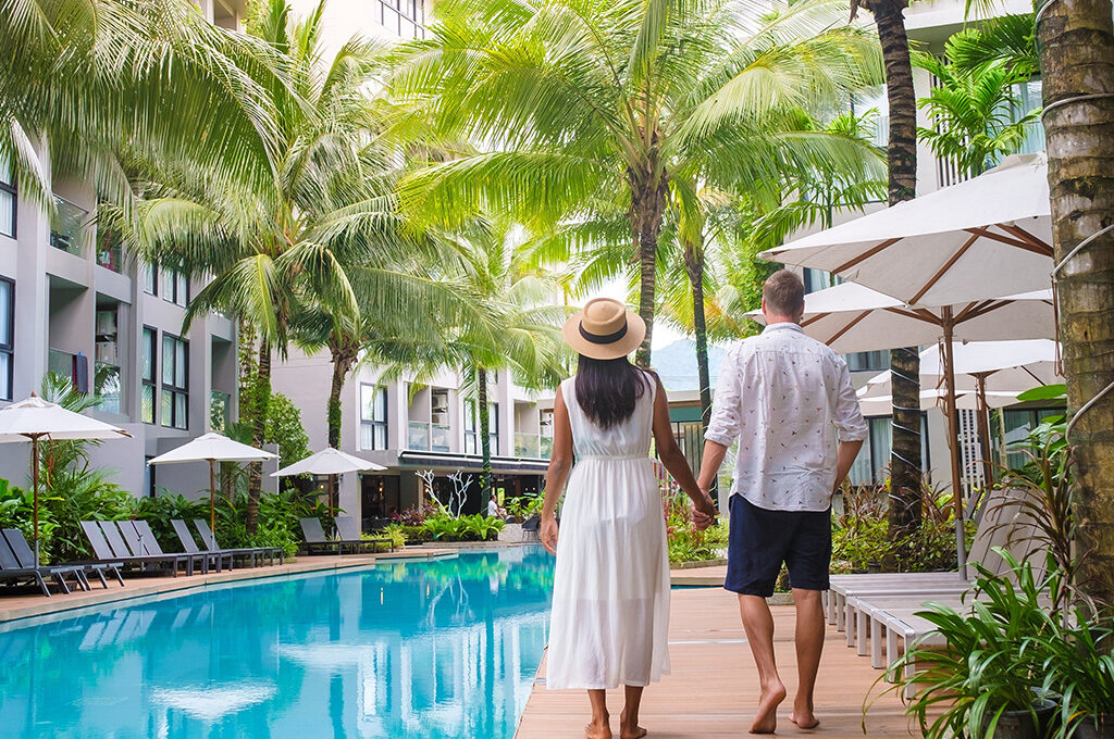 Couple walking hand-in-hand along a tropical resort pool, highlighting romantic stays at the best hotels in mauritius.