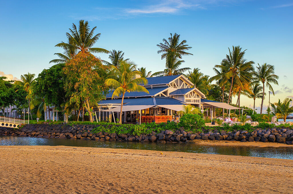 Oceanfront restaurant and wooden bridge surrounded by palm trees at one of the best hotels in mauritius.